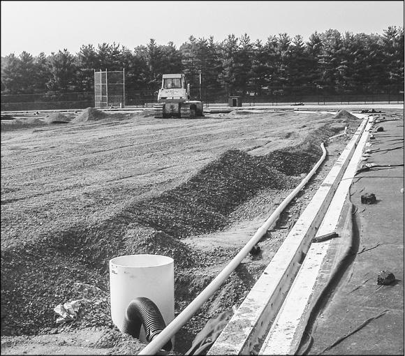 Once the field is leveled, a covering is placed over the soil to prevent weeds from coming through. Then, drainage pipes and stones large enough to allow for percolation are added before the final field surface is installed.